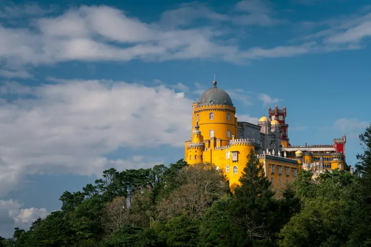 The red and yellow towers of Pena Palace against a blue sky